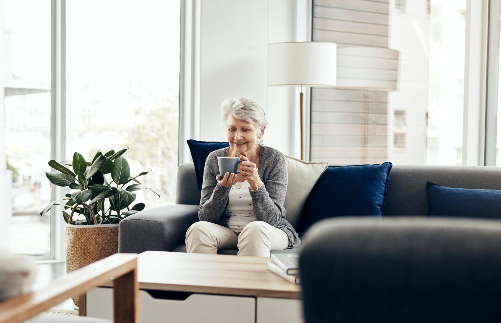 Personne âgée souriante et sereine chez elle, illustrant le maintien à domicile en toute sécurité grâce à la téléassistance Jadis.